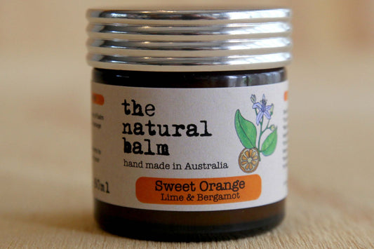 Jar of 'the natural balm' with a label indicating it's made in Australia, featuring sweet orange, lime, and bergamot.