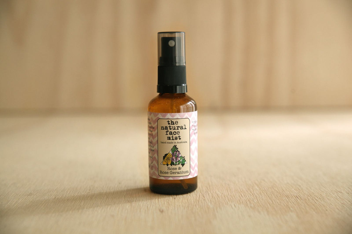 Bottle of 'The Natural Face Mist' on a wooden surface with a neutral background
